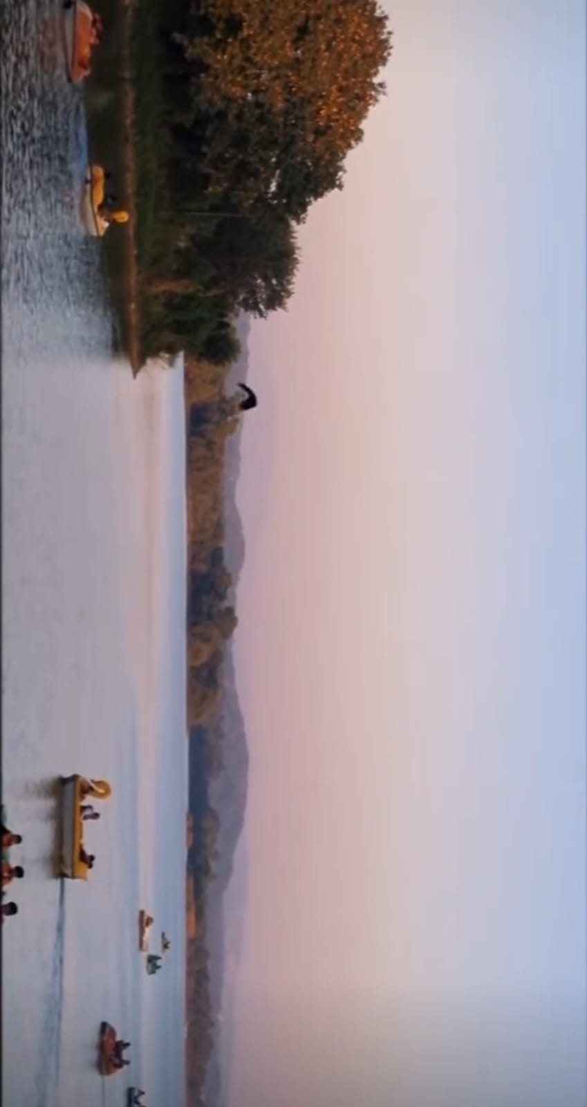 A photo of boats on a lake beneath a pastel evening sky.